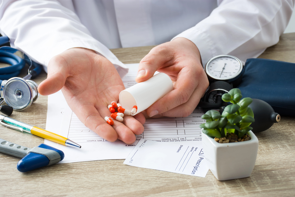 Avoiding medical claims Healthcare provider pouring red and white capsules from a pill bottle onto their palm at a medical desk