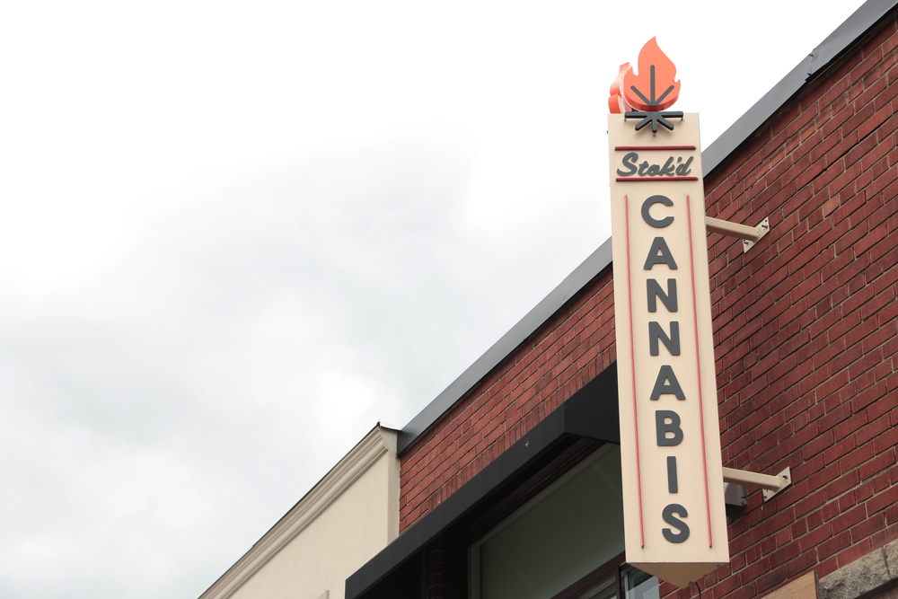 Licensed Michigan dispensaries Stok'd Cannabis retail dispensary blade sign mounted on red brick building exterior